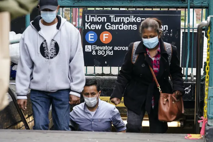 Masked commuters emerging from a subway station in Kew Gardens, one of Cuomo's hotspots.